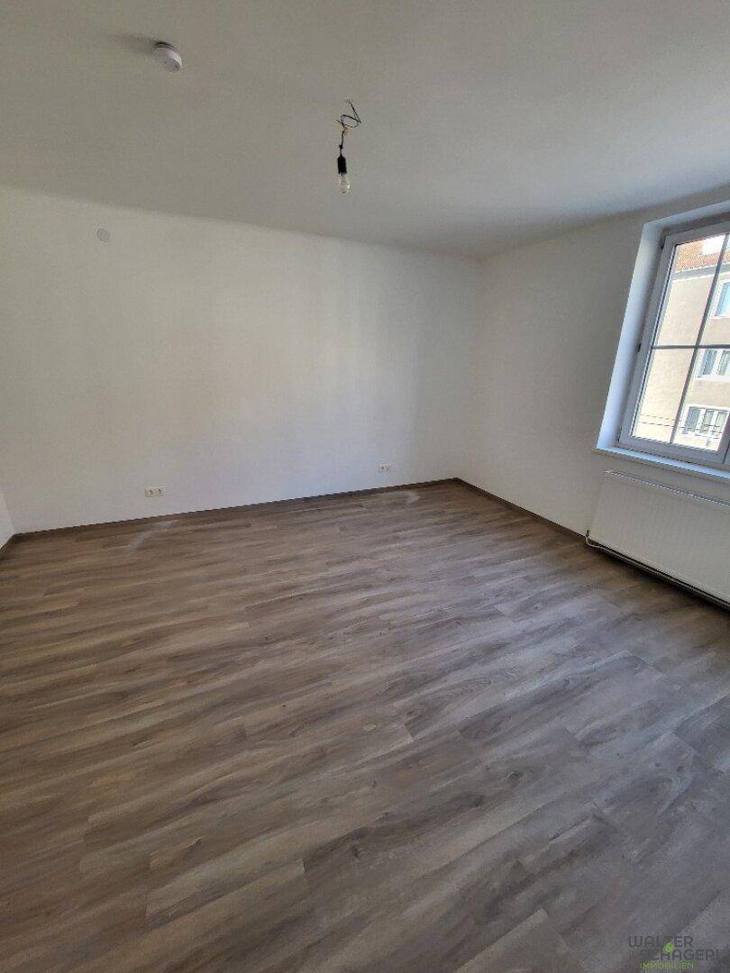 Unmöbliertes Schlafzimmer mit Laminatboden und einem Fenster, das eine angenehme Helligkeit bietet.