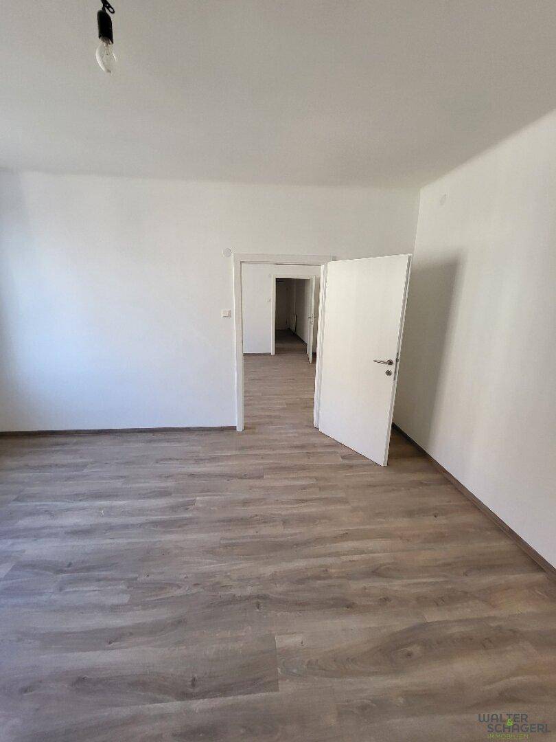 Großes, unmöbliertes Zimmer mit Laminatboden und weiß gestrichenen Wänden, ideal für individuelle Gestaltung.
