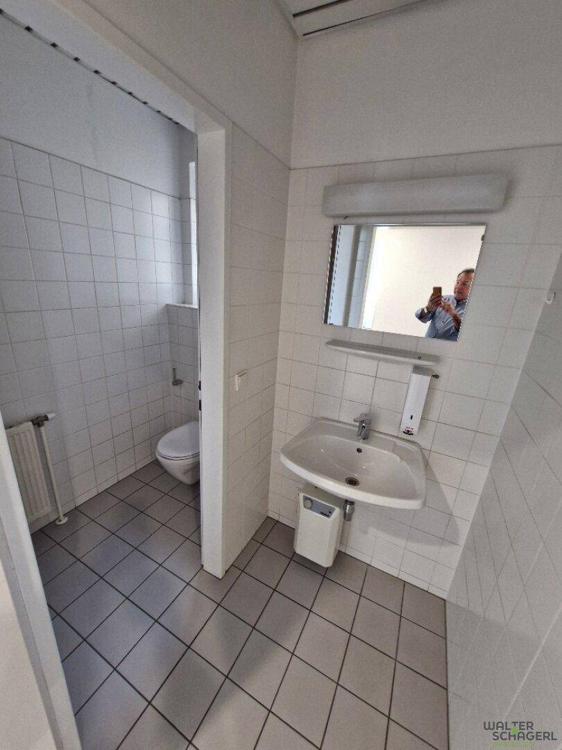 Funktionales Badezimmer mit Waschbecken, Spiegel und weißen Fliesen, sauber und gut gepflegt.