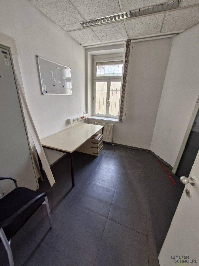 Kleines, funktionales Büro mit Schreibtisch, Bürostuhl und Fenster, ideal für Einzelarbeit.