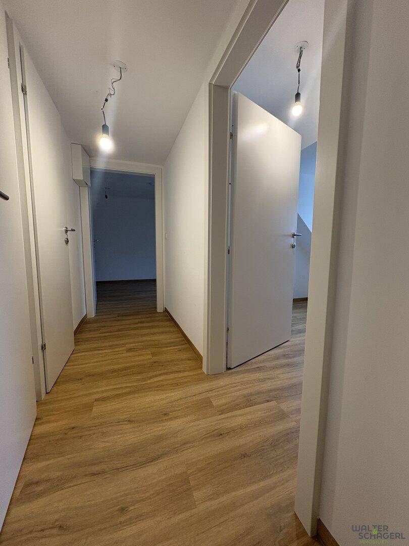 Heller Flur mit Laminatboden und mehreren Türen zu angrenzenden Räumen.