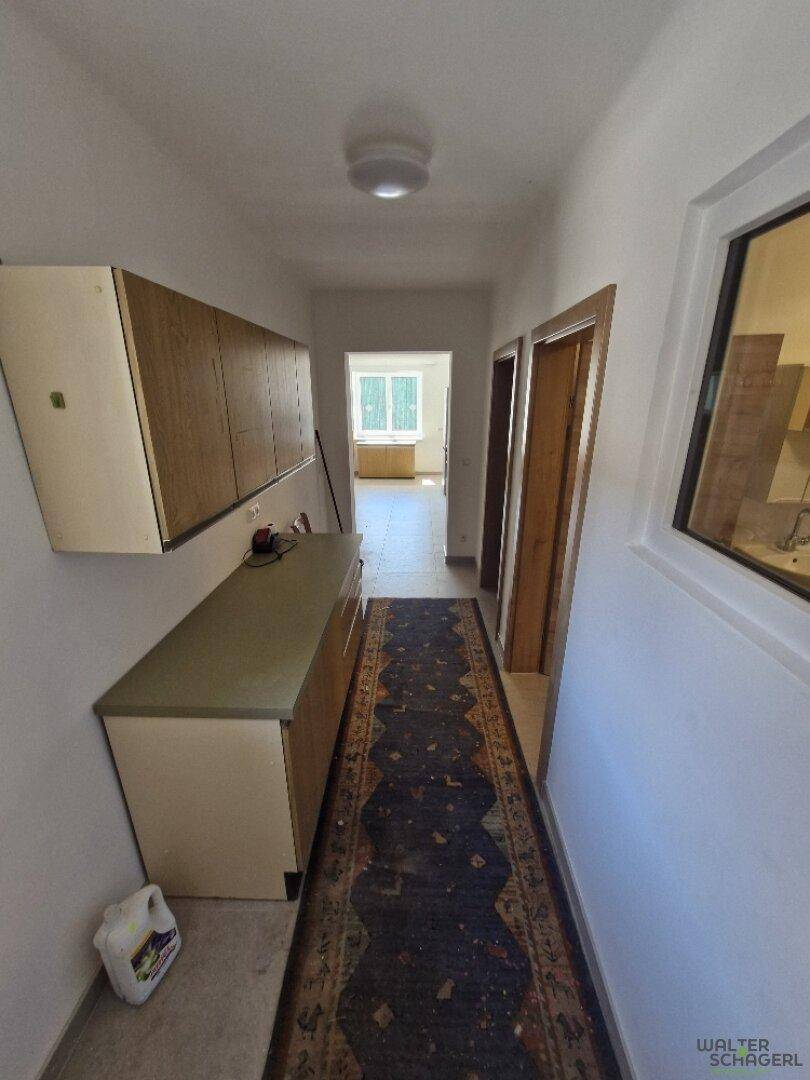 Langer Flur mit Teppichläufer, Einbauschränken und Blick in einen weiteren Raum.