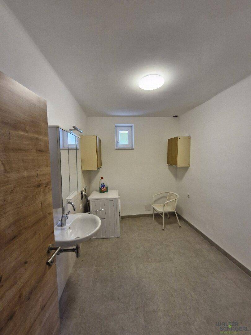 Heller Hauswirtschaftsraum mit Waschbecken, Waschmaschine und kleinem Fenster.