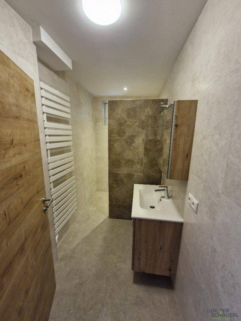 Modernes Badezimmer mit begehbarer Dusche, Einzelwaschbecken und beheiztem Handtuchhalter.