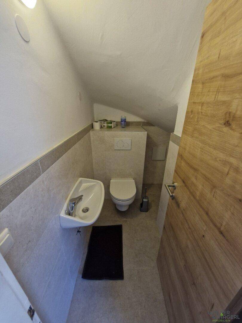 Kleines Gäste-WC mit Wand-WC, Waschbecken und Dachschräge.