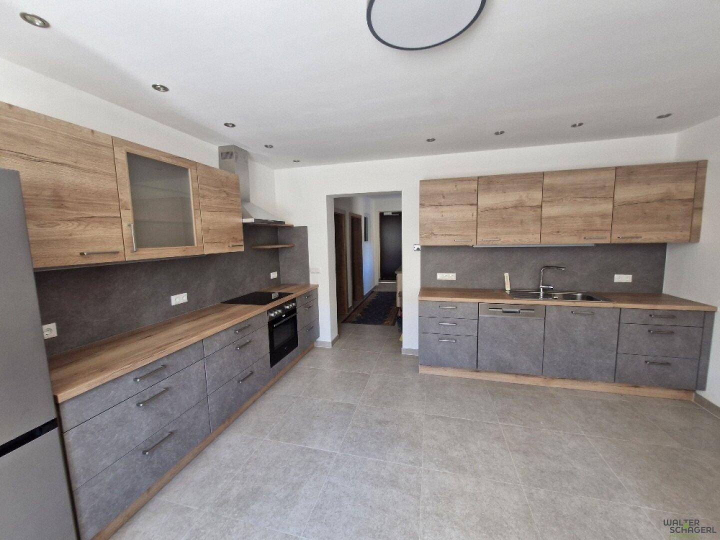 Moderne Küche mit Holz- und Steindekor, integrierten Geräten und Fliesenboden.