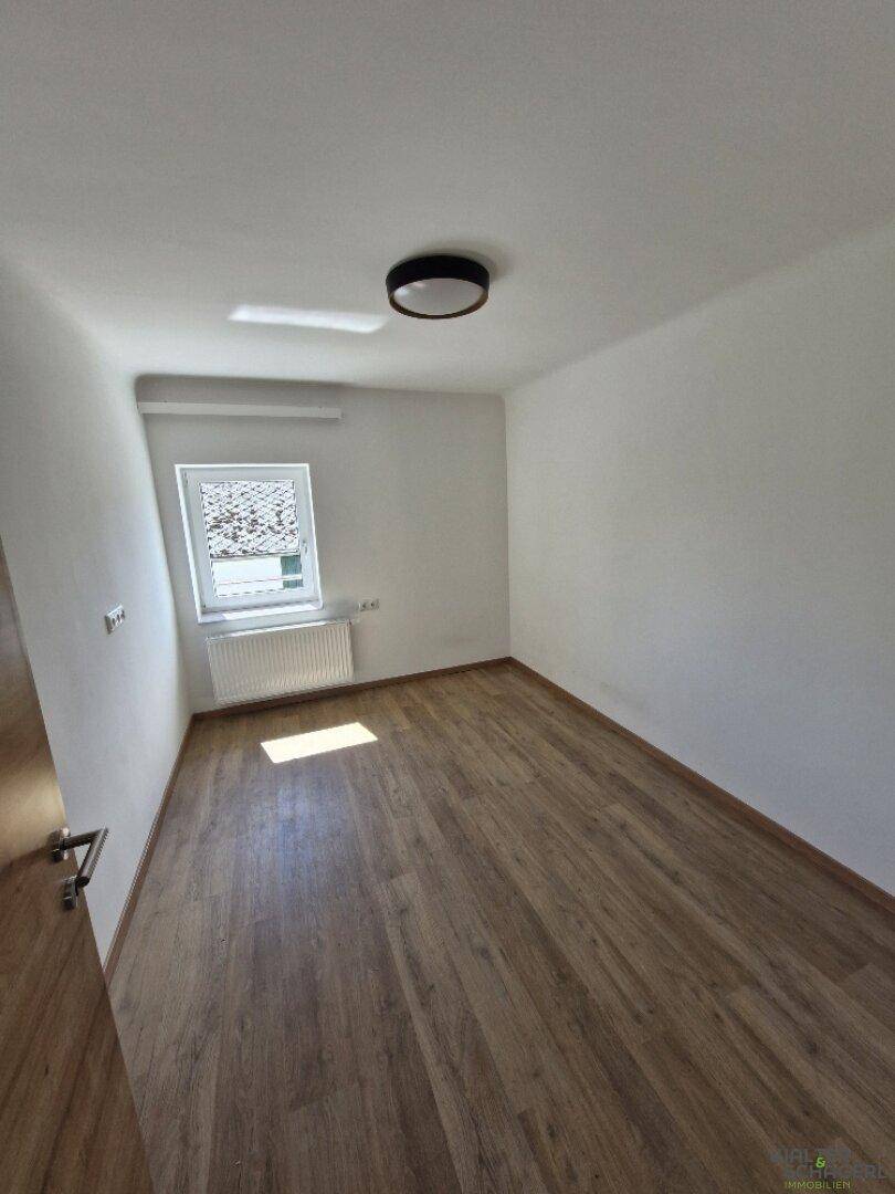 Helles Schlafzimmer mit Holzboden, Fenster und Heizkörper, bereit zur Einrichtung.