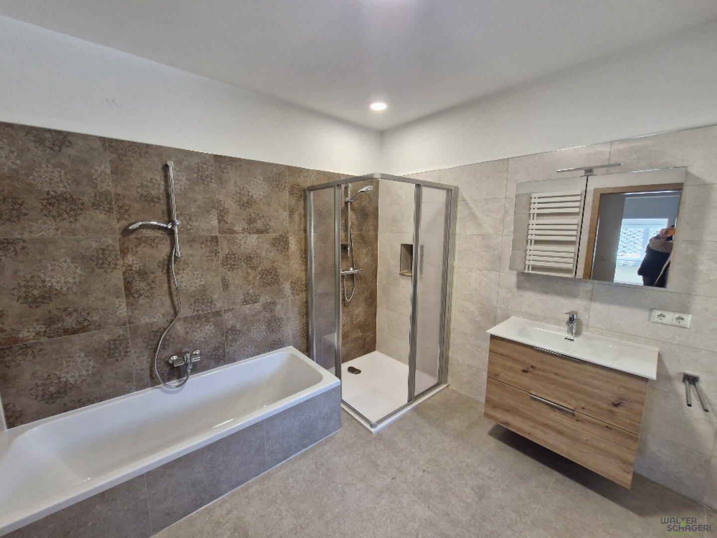 Geräumiges Badezimmer mit Badewanne, Duschkabine, Einzelwaschbecken und beheiztem Handtuchhalter.
