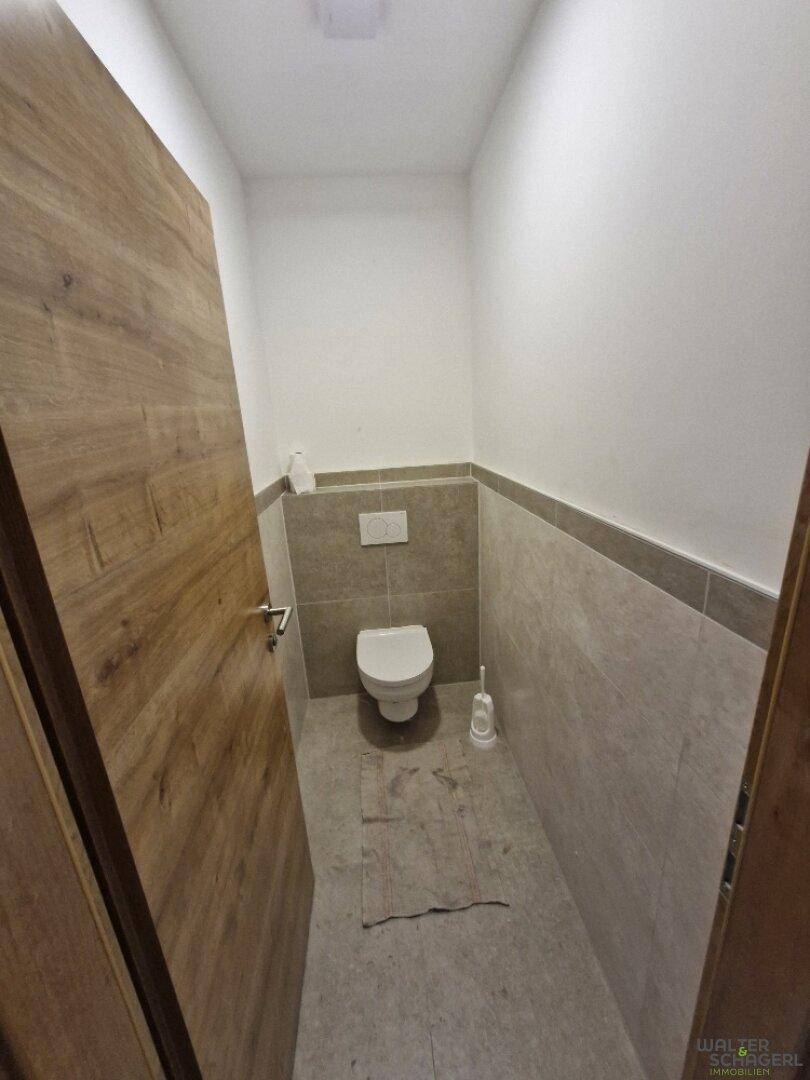 Modernes Gäste-WC mit Wand-WC und Fliesen an Wänden und Boden.