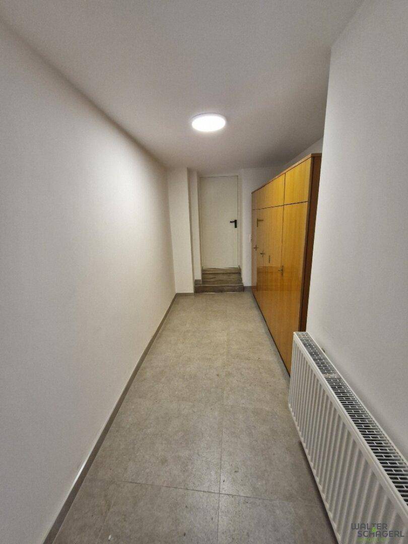 Heller Flur mit Fliesenboden, Heizkörper und Zugang zu weiteren Räumen.