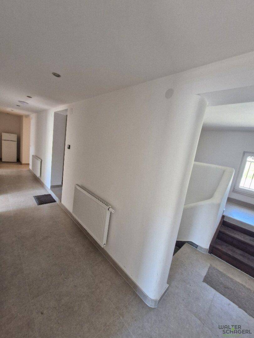 Heller Flur mit Fliesenboden und elegant geschwungener Treppe zum Obergeschoss.
