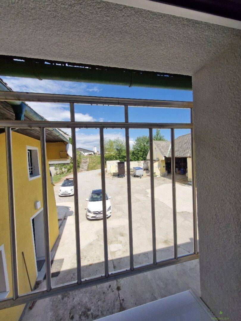 Blick aus dem Fenster auf den gepflasterten Innenhof mit parkenden Autos.