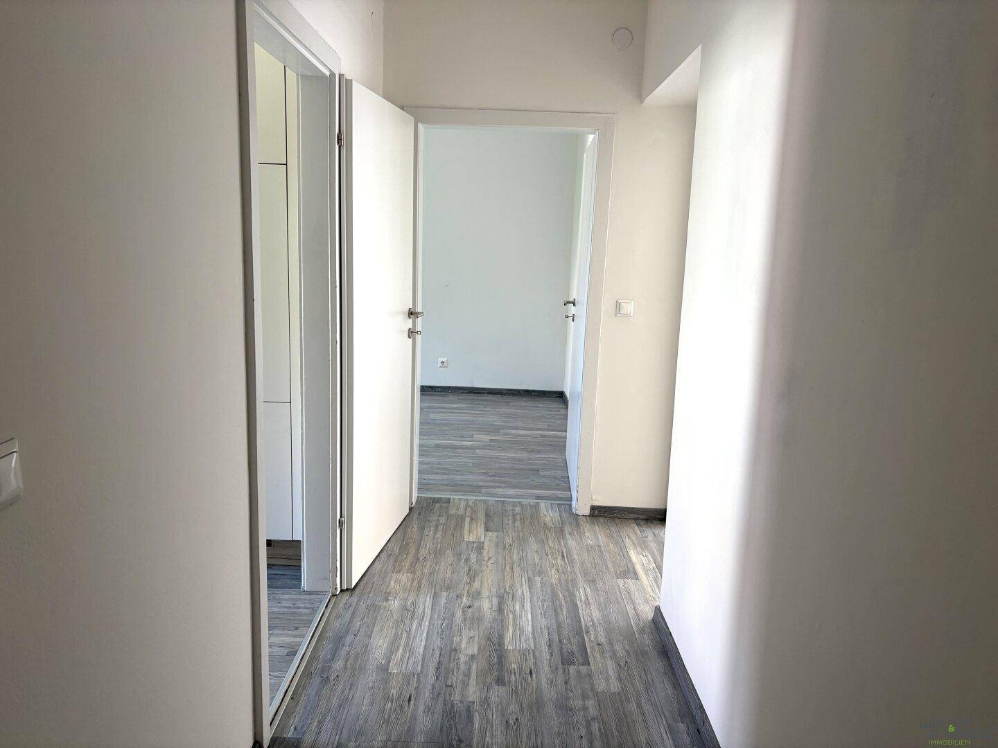 Heller Flur mit Laminatboden und Türen, die zu den verschiedenen Zimmern führen.