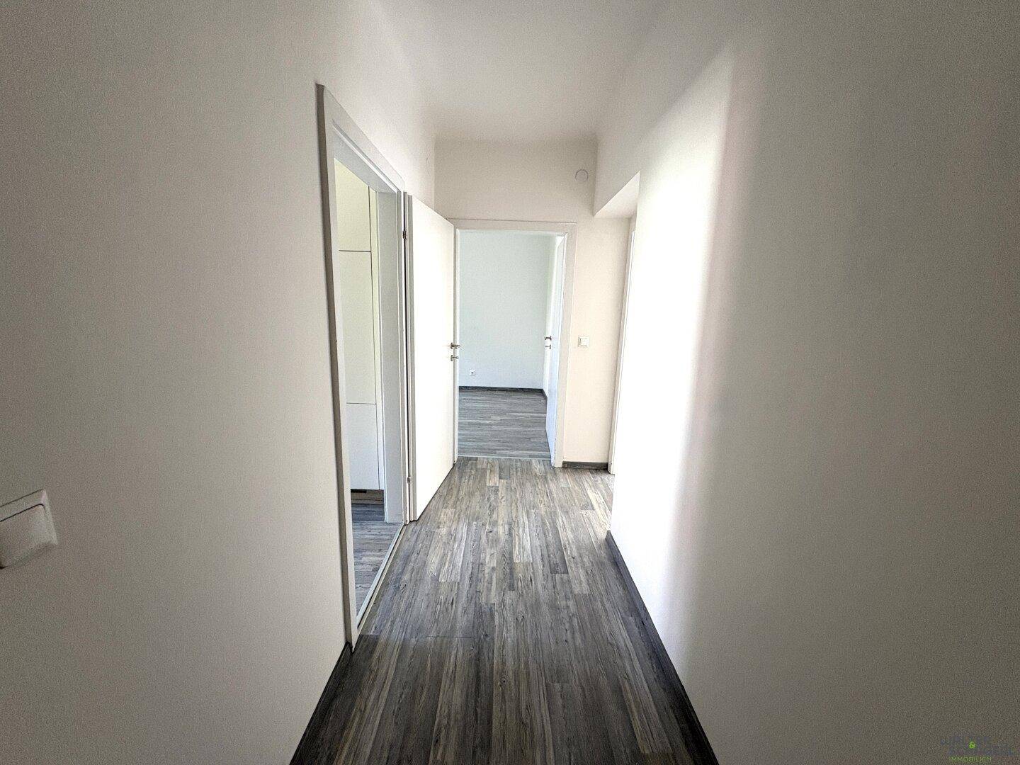 Langer, heller Flur mit Laminatboden und Zugang zu weiteren Räumen der Wohnung.
