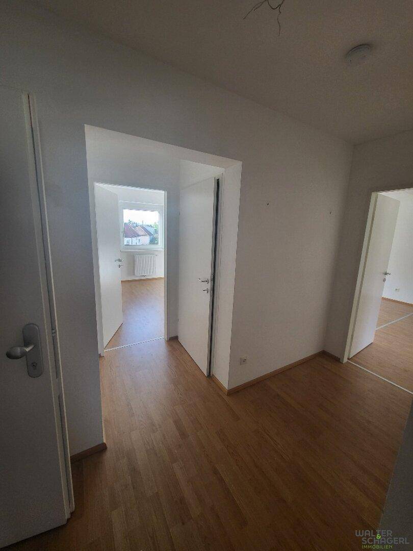 Zentraler Bereich mit hellem Holzfußboden und mehreren Türen, die zu angrenzenden Zimmern führen.
