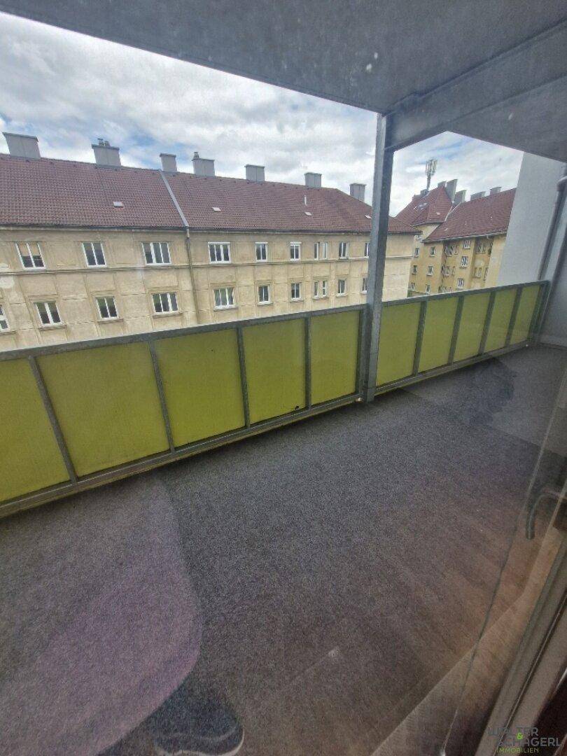 Balkon mit Blick auf die umliegenden Gebäude und gelb-grüner Brüstung.