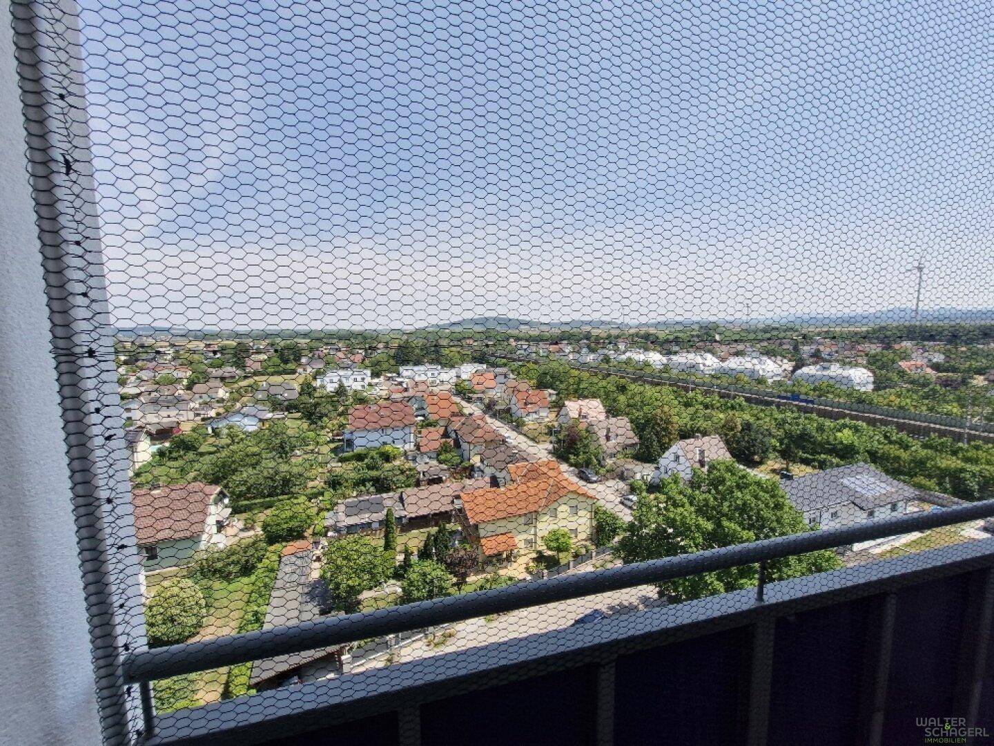 Weitblick vom Balkon über eine grüne Wohnsiedlung mit vielen Häusern und Bäumen.