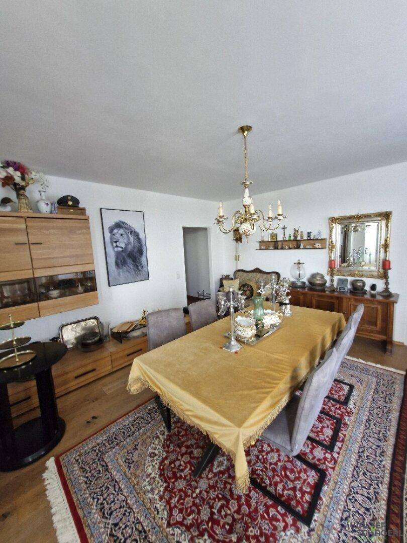 Eleganter Essbereich mit großem Esstisch, Kronleuchter und traditionellem Teppich auf Parkettboden.