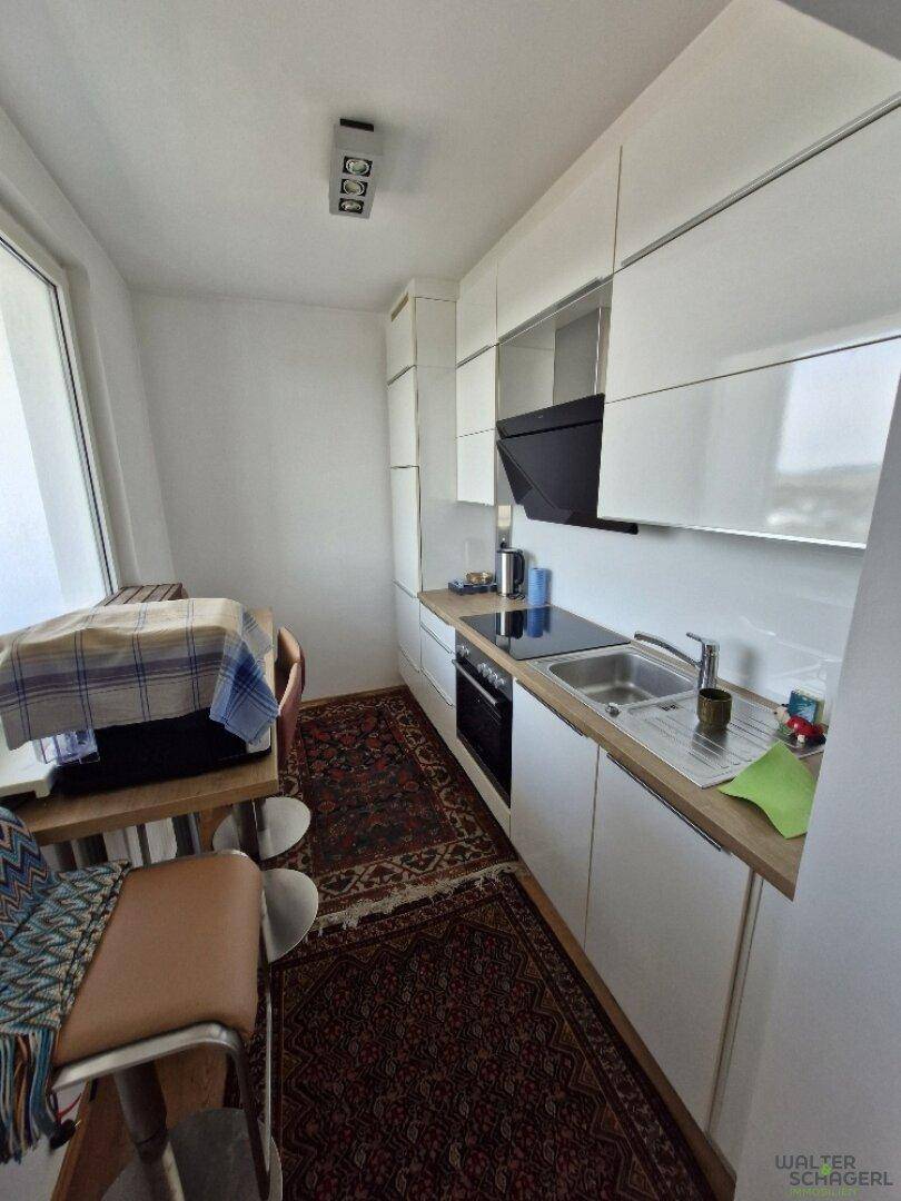 Helle Einbauküche mit modernen weißen Fronten, Holzarbeitsplatte und Platz für einen kleinen Esstisch.