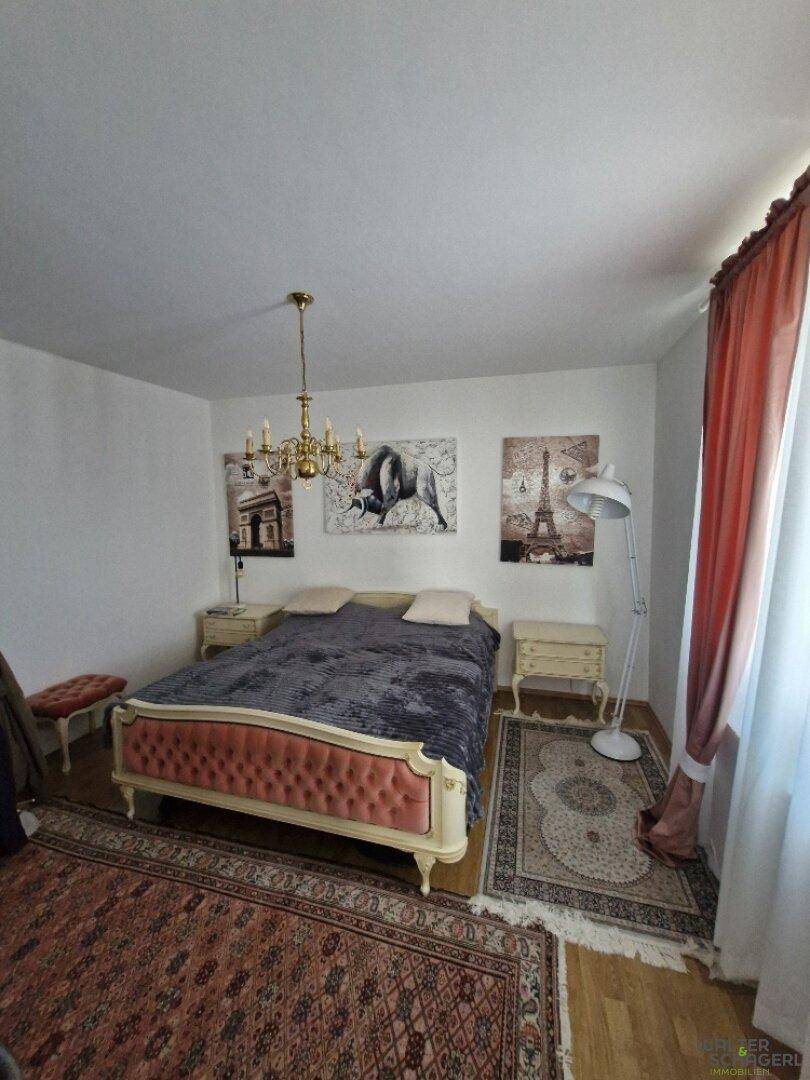 Gemütliches Schlafzimmer mit Doppelbett, Nachttischen und klassischer Einrichtung auf Holzparkett.