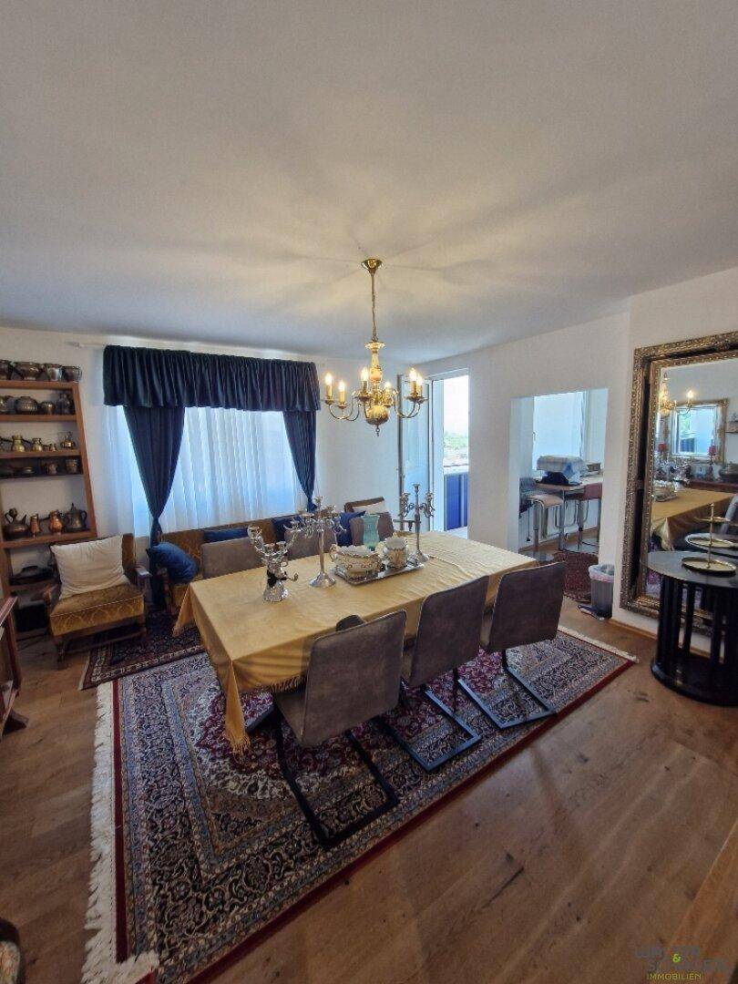 Geräumiges Wohnzimmer mit Sofa, großem Spiegel und Blick auf den Außenbereich durch das Fenster.