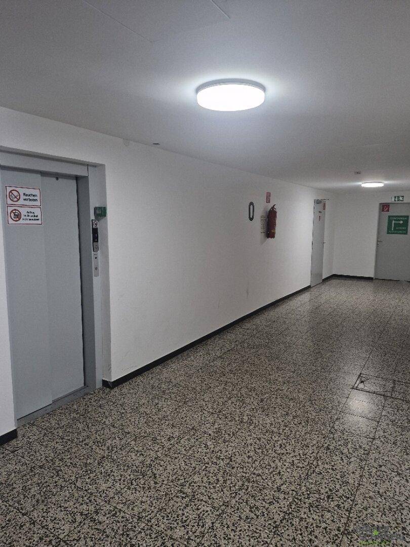 Heller Gemeinschaftsflur mit Aufzug und robustem Terrazzoboden in einem Mehrfamilienhaus.