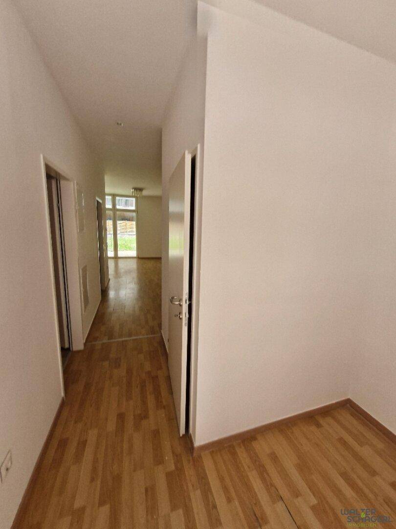 Heller Flur mit Holzfußboden und Zugang zu verschiedenen Räumen, der viel natürliches Licht hereinlässt.