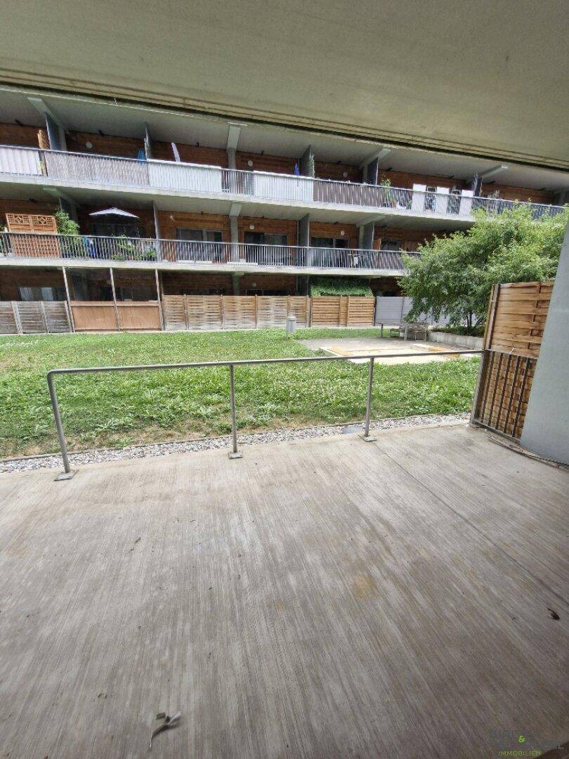 Geräumige Außenterrasse mit Betonboden und Blick auf die umliegenden Wohngebäude und Grünflächen.