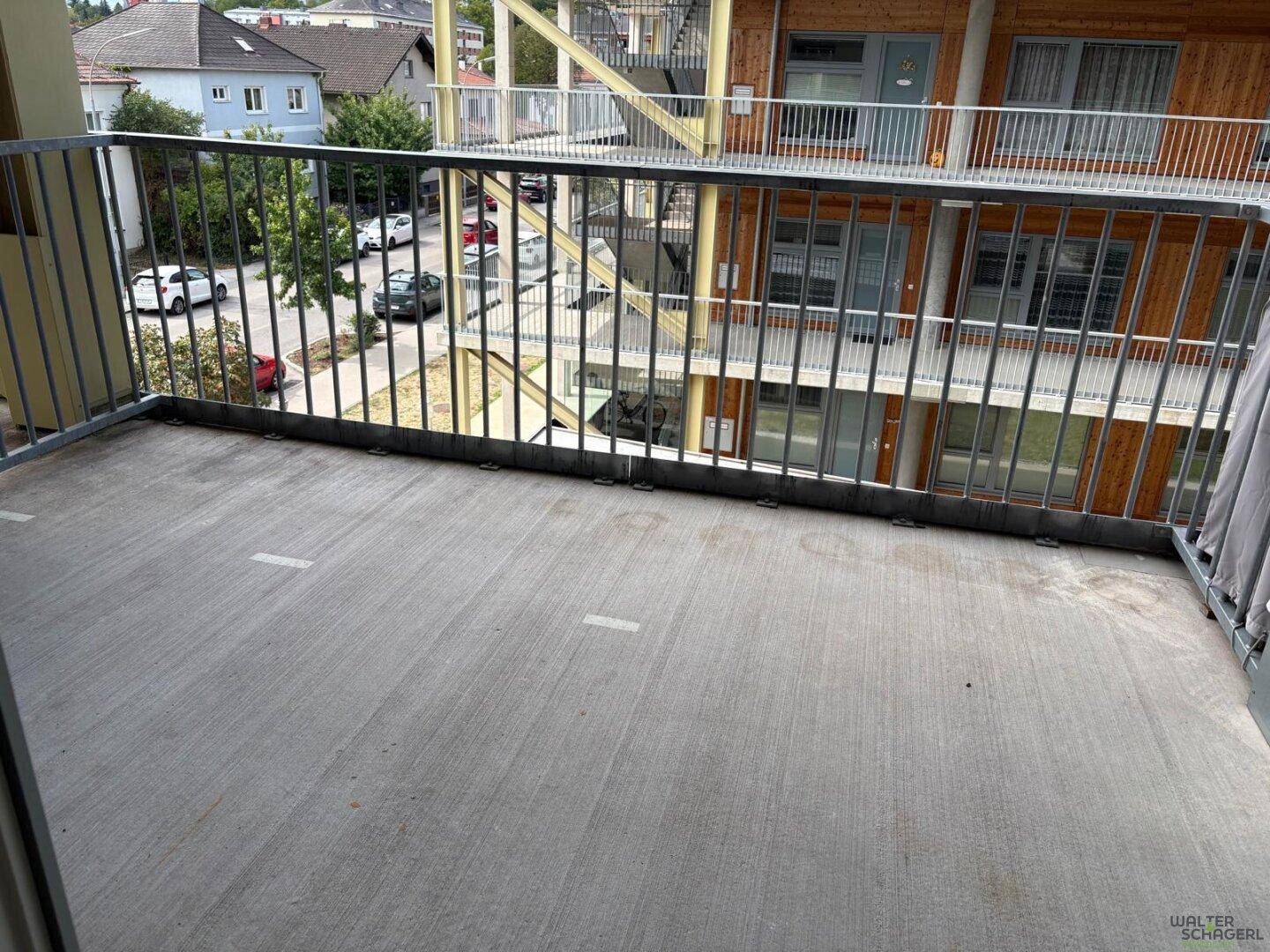 Geräumiger Balkon mit Metallgeländer und Blick auf die umliegende Wohnbebauung.