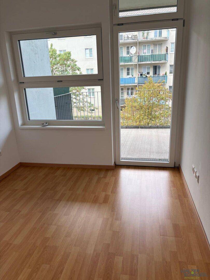 Heller Raum mit Laminatboden und großem Fenster, das viel Tageslicht hereinlässt.