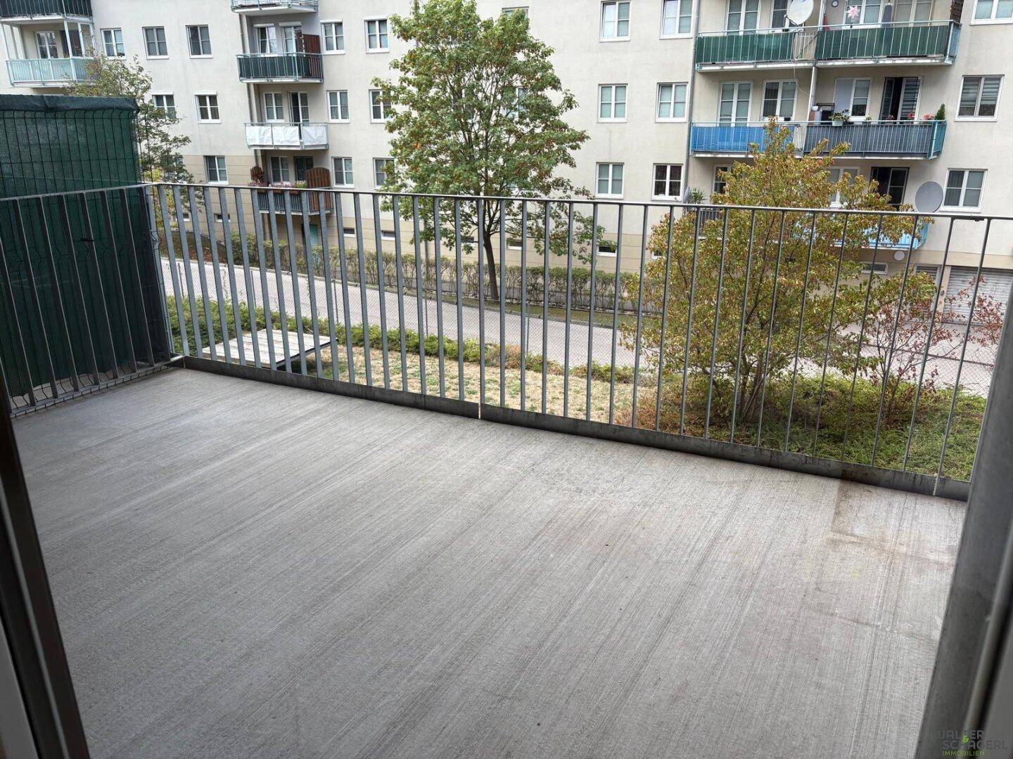 Geräumiger Balkon mit Betonboden und Blick auf die umliegenden Wohngebäude.