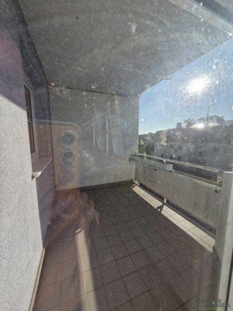 Balkon mit Fliesenboden und Blick auf die umliegenden Gebäude unter blauem Himmel.