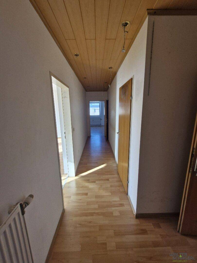 Heller Flur mit Holzboden und Holzdeckenverkleidung, der einen Durchblick zu weiteren Räumen bietet.