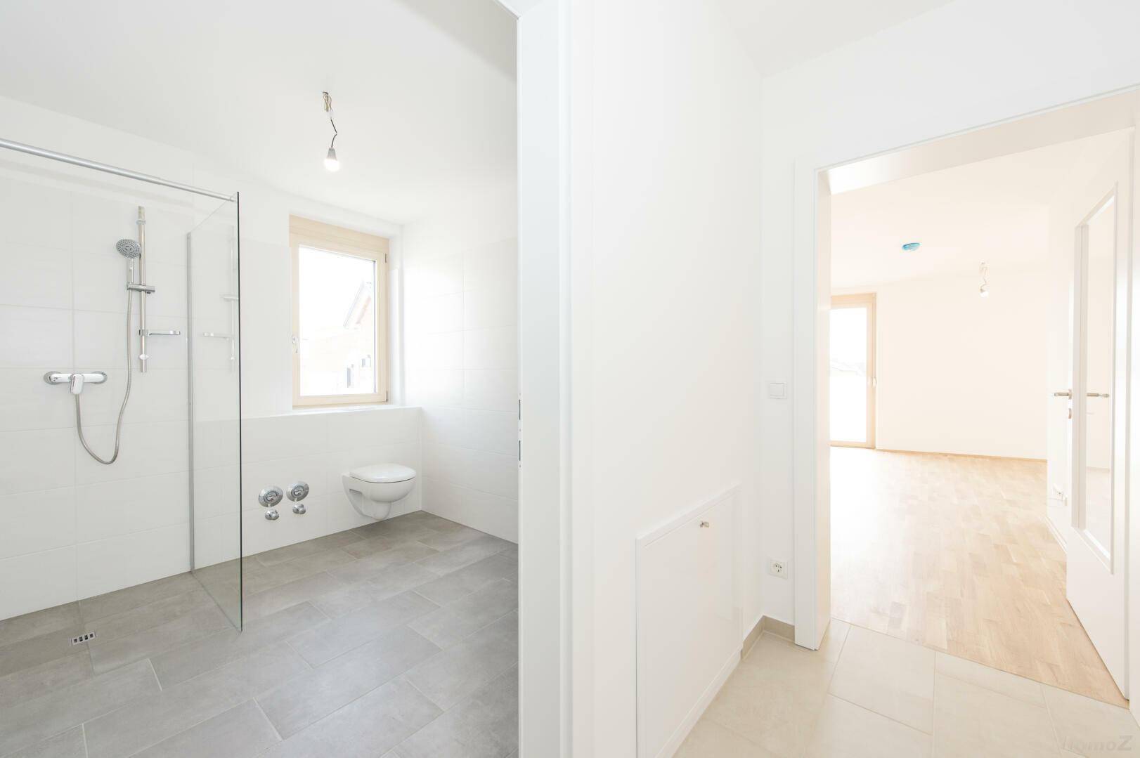 Modernes Badezimmer mit ebenerdiger Dusche, wandhängendem WC und Fenster.