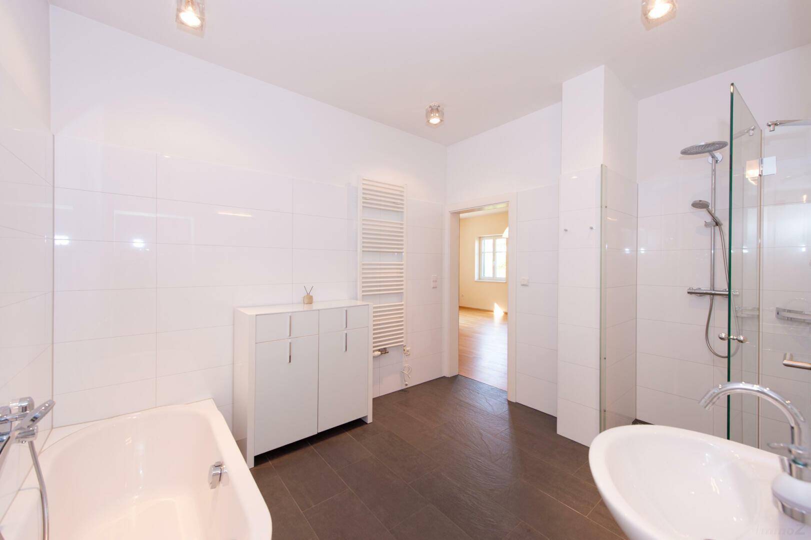 Geräumiges Badezimmer mit Badewanne, Dusche und Waschbecken, modern gefliest.