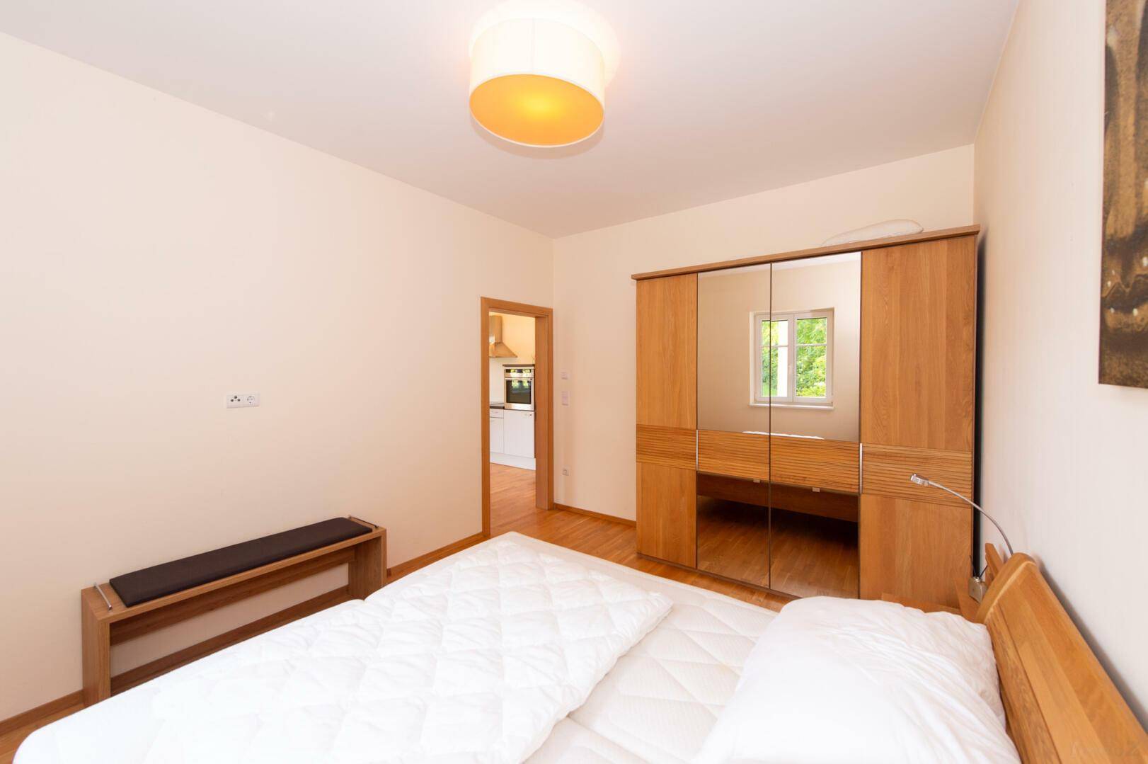 Schlafzimmer mit großem Holzschrank und Parkettboden, hell und freundlich gestaltet.