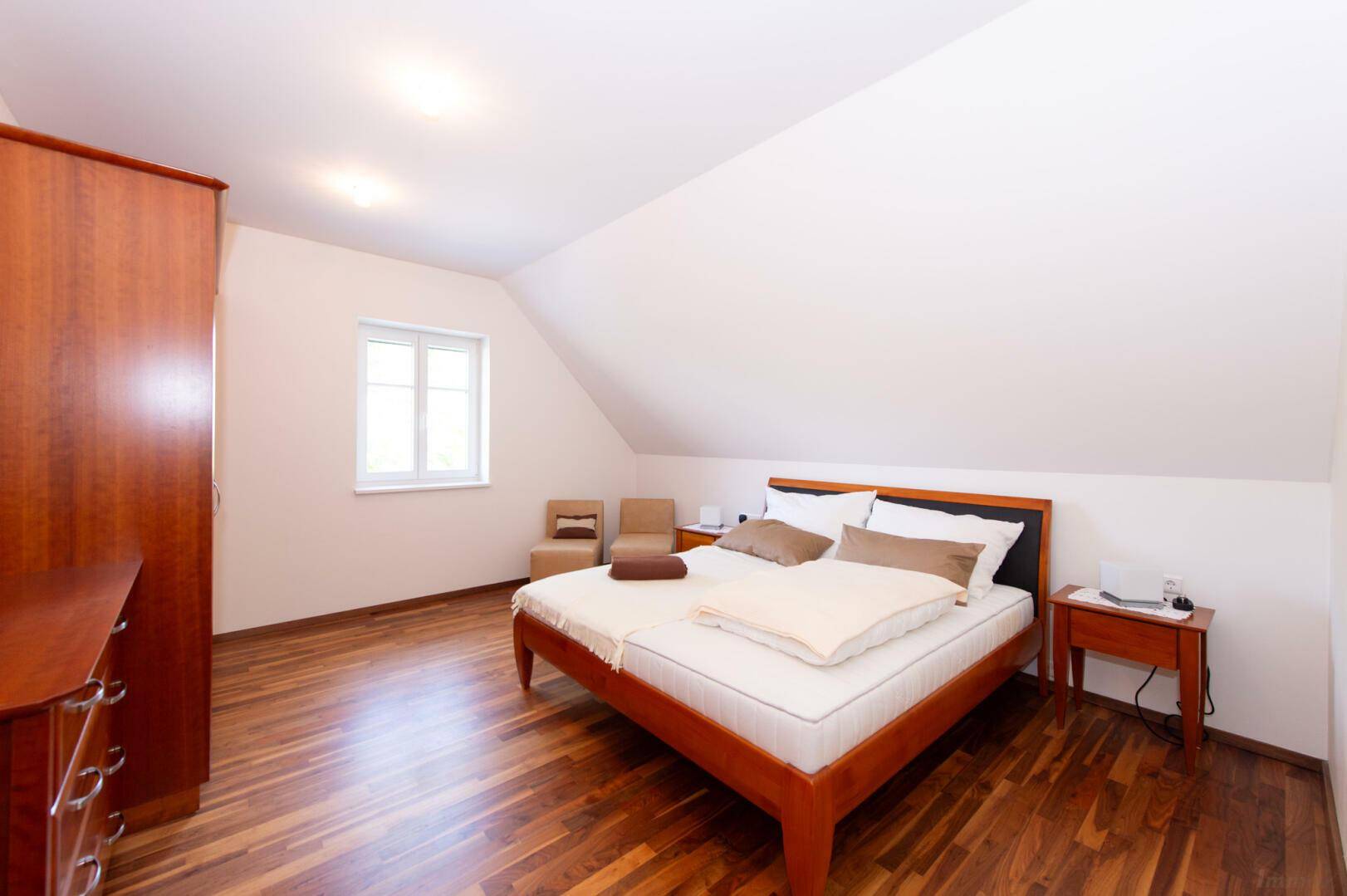 Schlafzimmer im Dachgeschoss mit Holzboden, Doppelbett und Dachschrägen, hell und gemütlich.