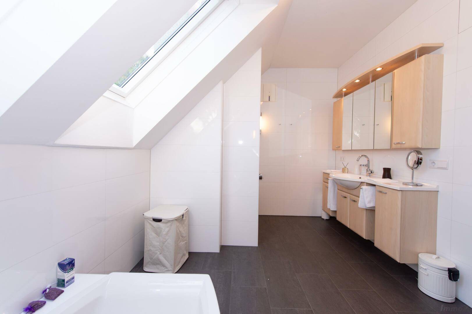 Geräumiges Badezimmer im Dachgeschoss mit Doppelwaschbecken, Spiegelschrank und Dachfenster.