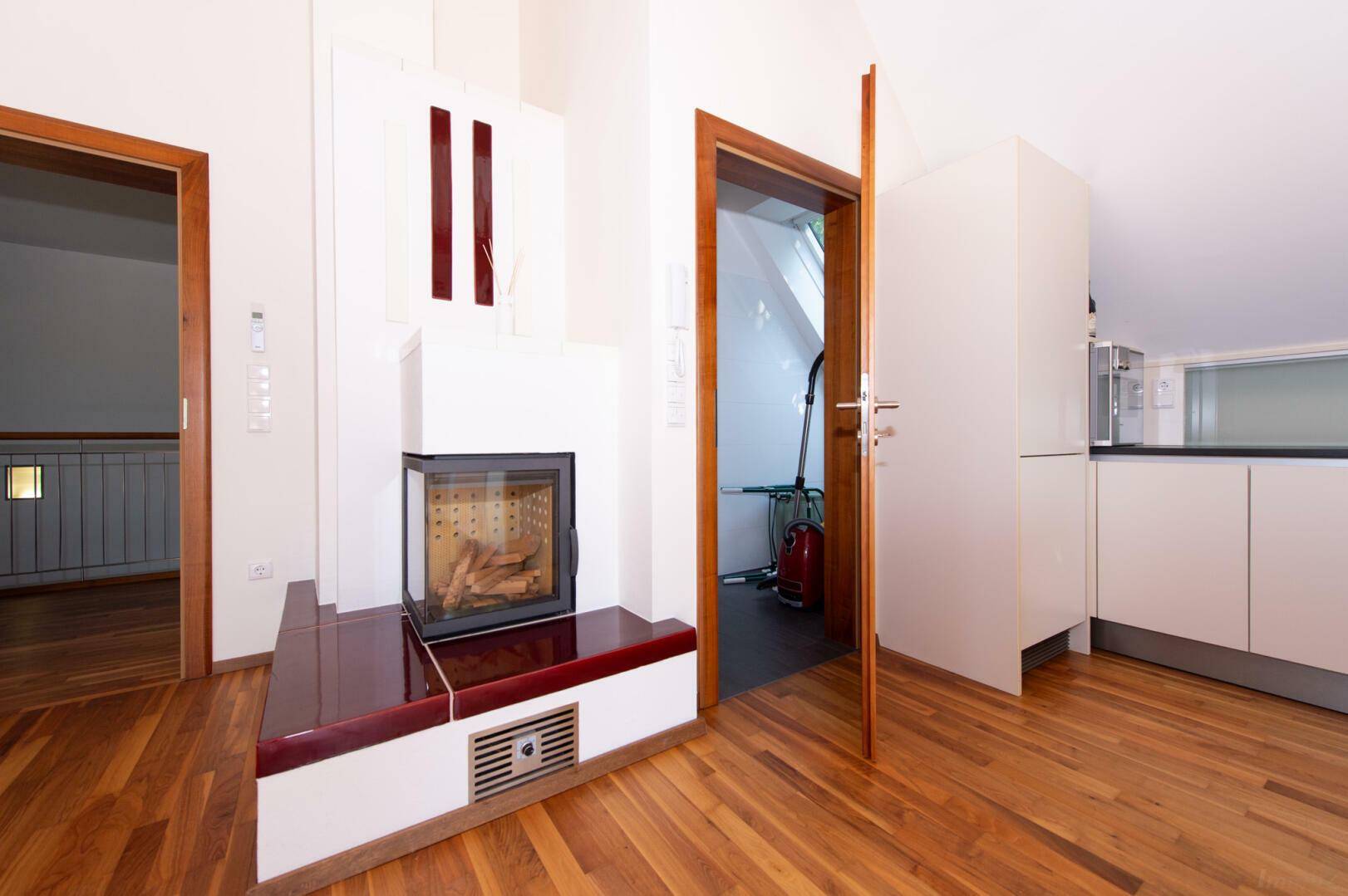 Moderner Kamin im offenen Wohnbereich des Dachgeschosses, mit Holzboden und weißer Wand.