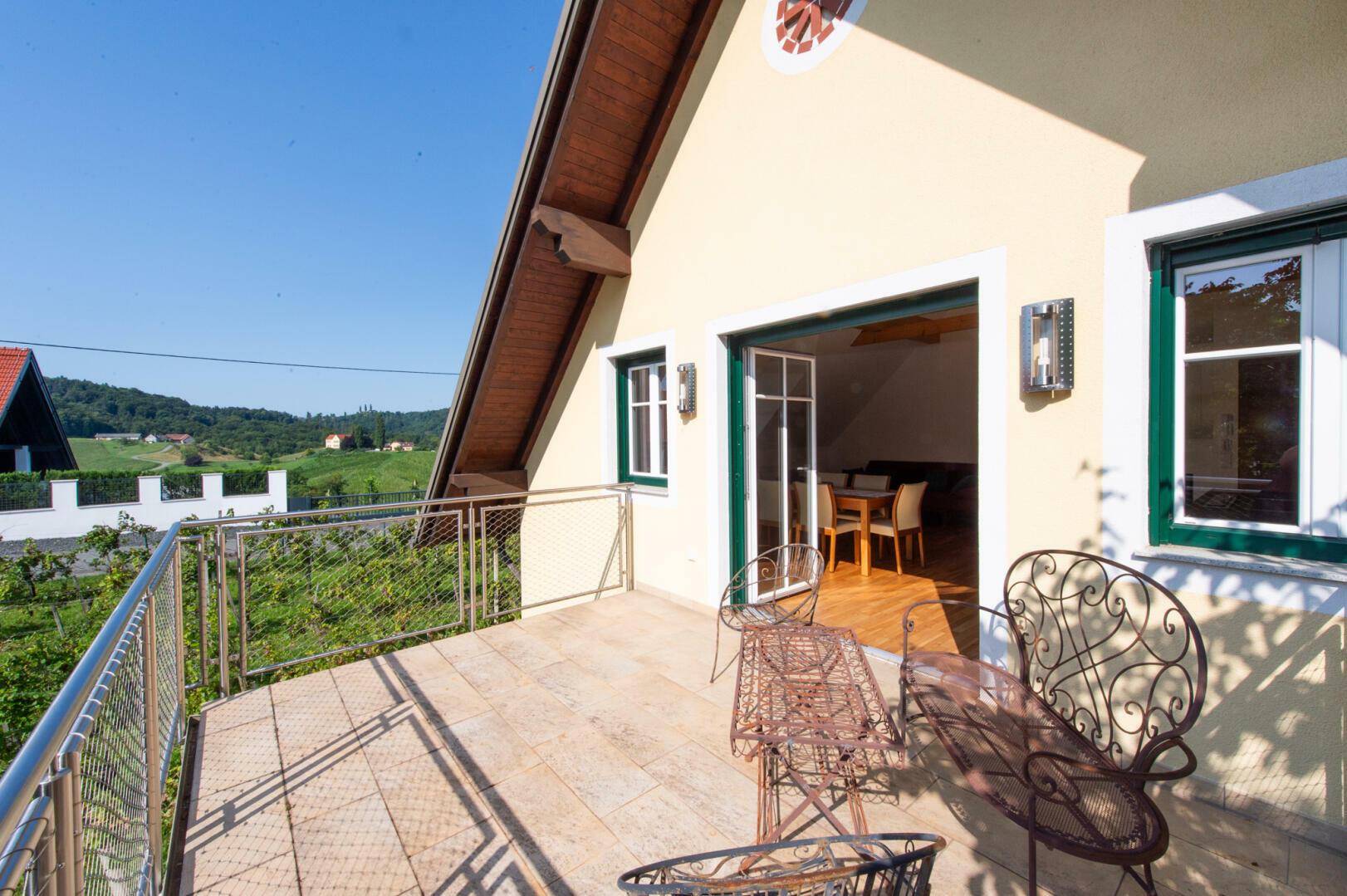 Geräumiger Balkon mit Metallgeländer und Gartenmöbeln, bietet weite Aussicht.