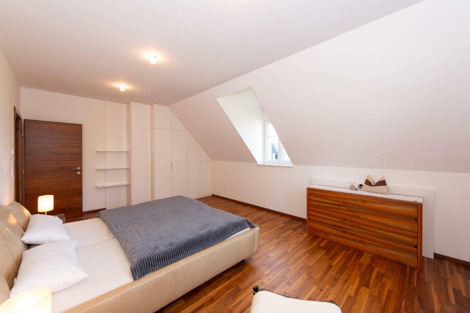 Schlafzimmer im Dachgeschoss mit Einbauschränken und Holzboden, hell und funktional.