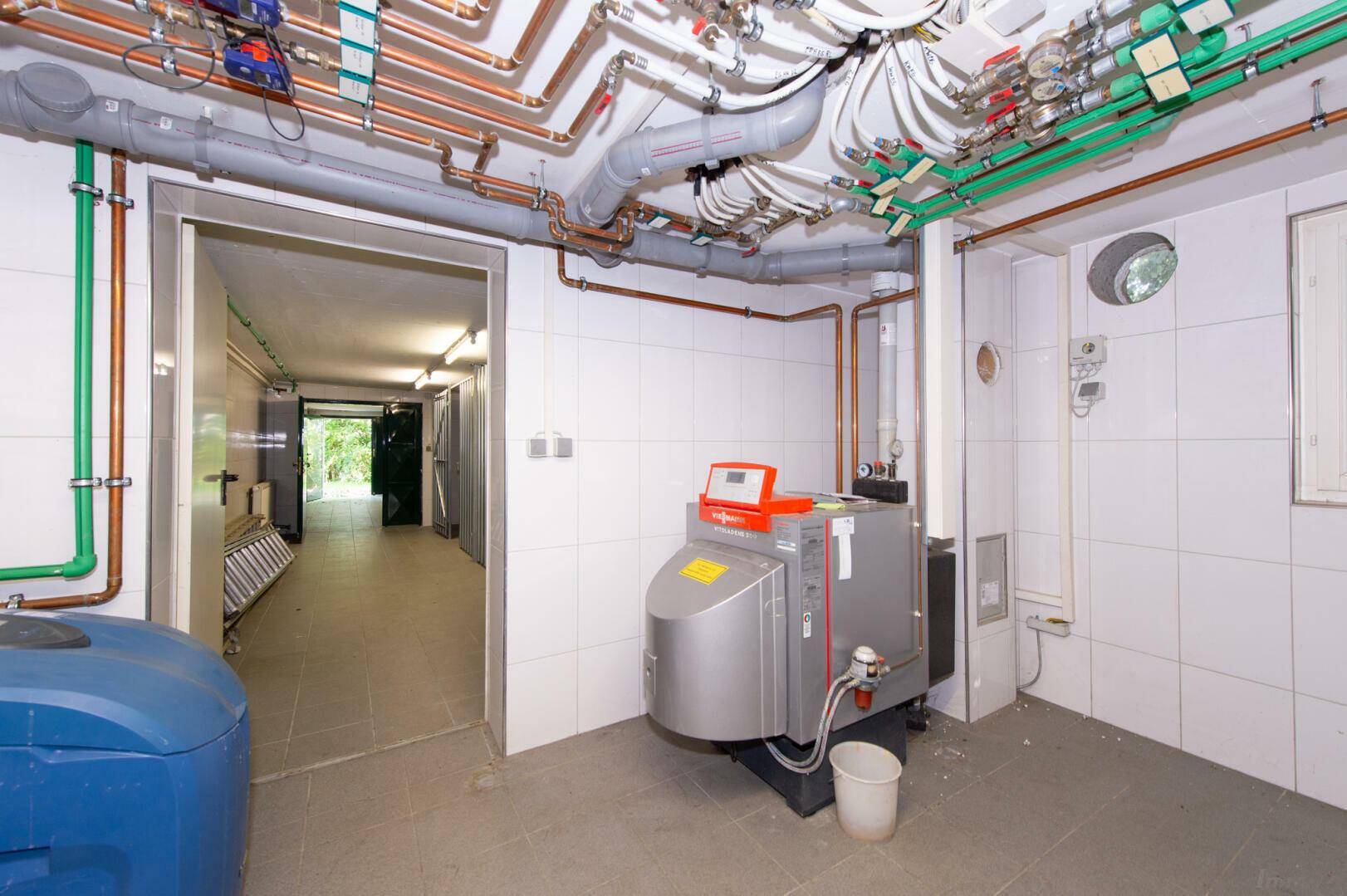 Heizungsraum im Keller mit moderner Heizungsanlage und sichtbaren Rohrleitungen.