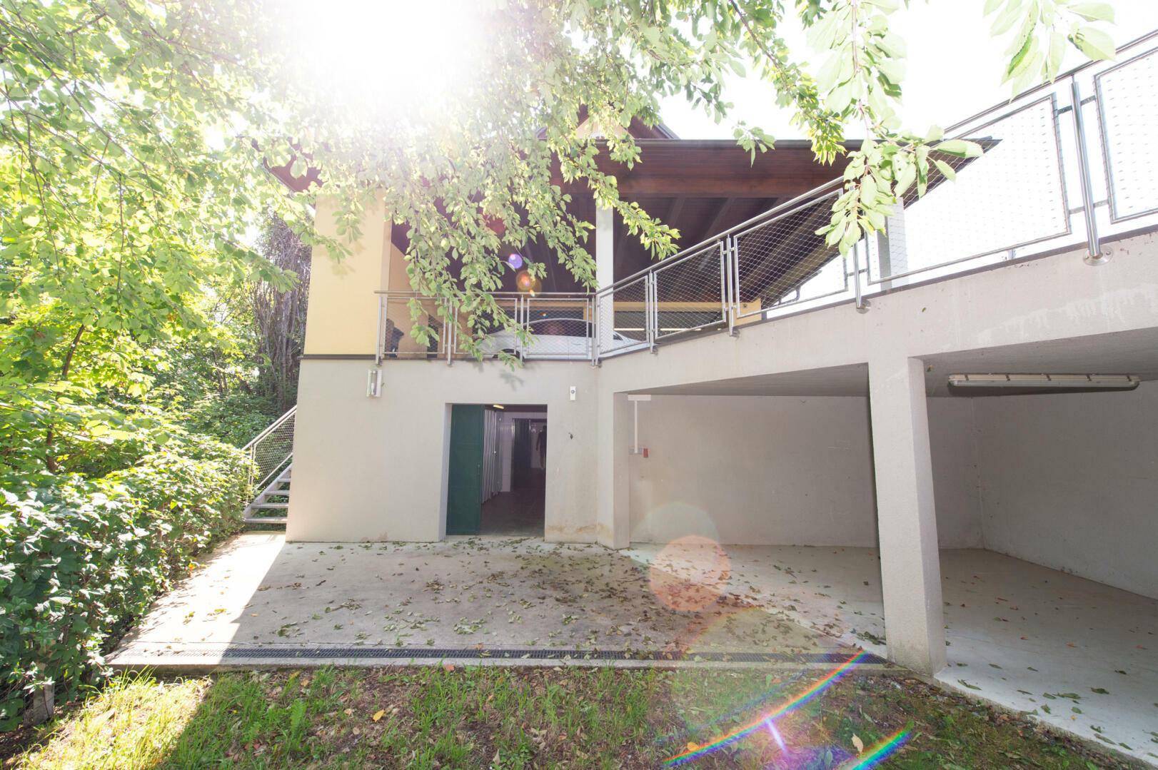 Unterer Bereich des Hauses mit Garagenzugang und Außentreppe, umgeben von Grün.