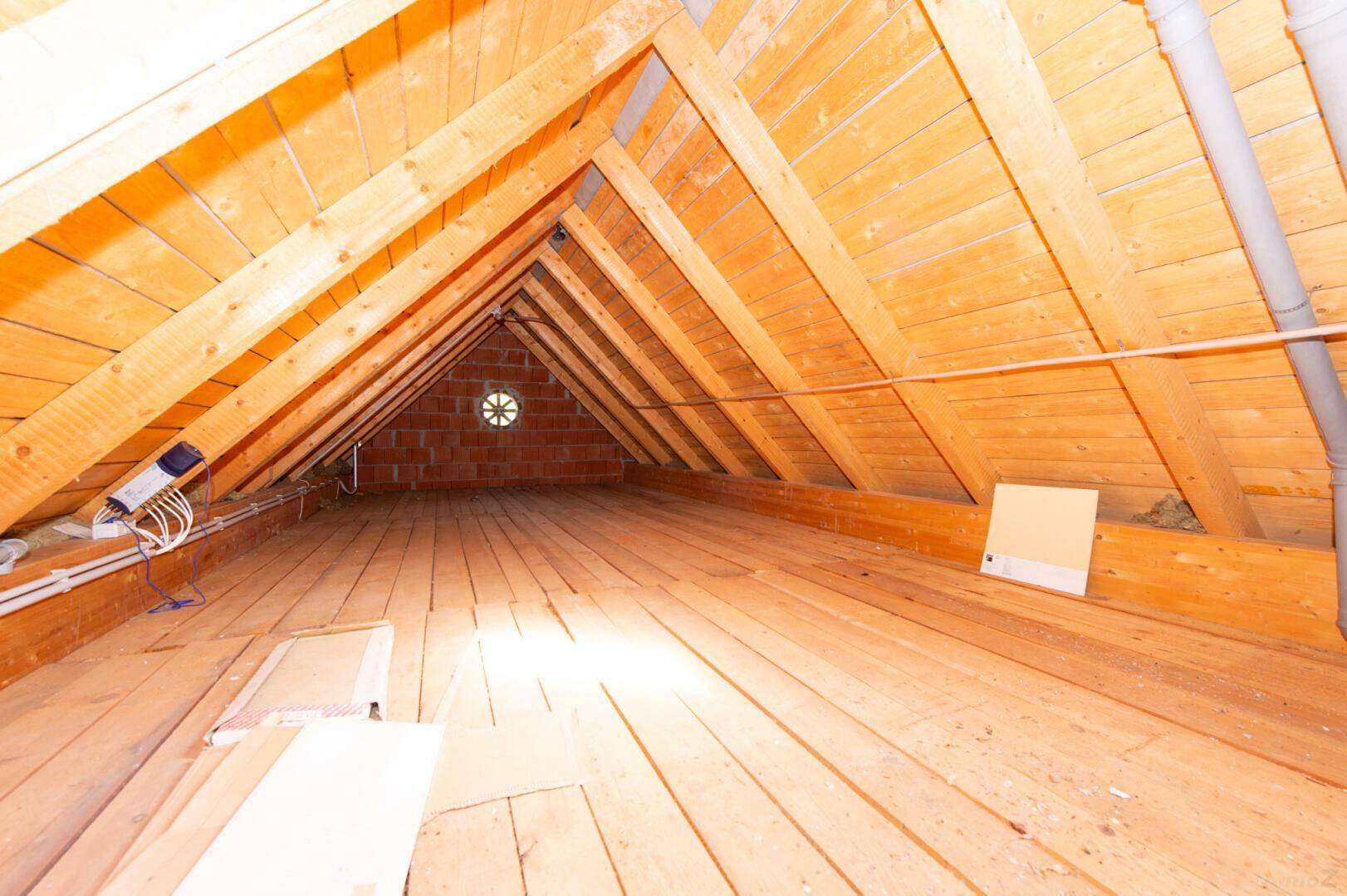 Unausgebauter Dachboden mit sichtbaren Holzbalken und Holzfußboden, viel Potenzial.