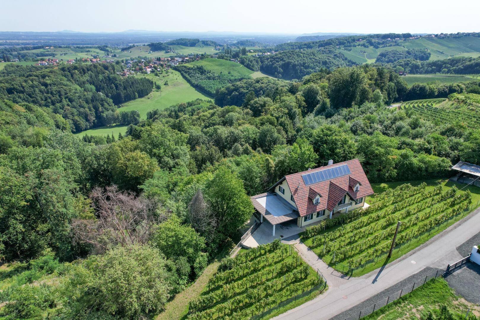 Weitläufige Luftaufnahme des Hauses inmitten von Weinbergen und bewaldeten Hügeln.