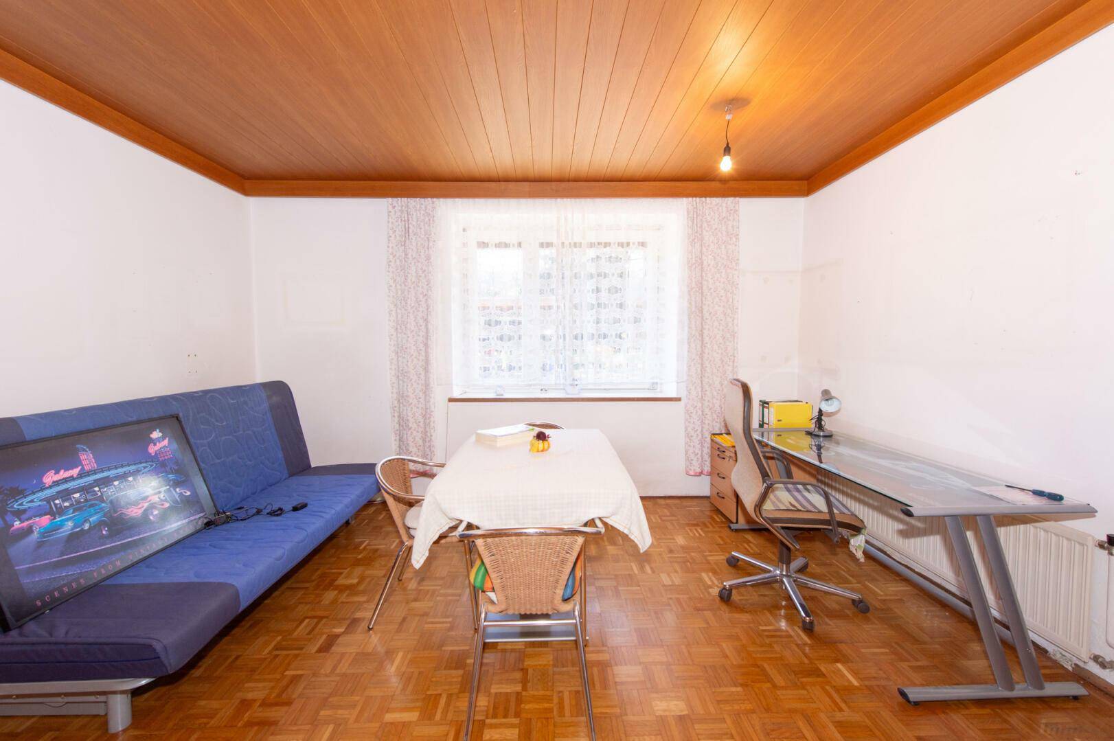 Vielseitiges Zimmer mit Parkettboden, Holzdecke und einem Schlafsofa.