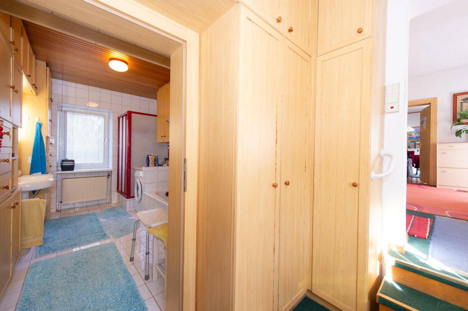 Hauswirtschaftsraum mit Waschbecken, vielen Holzschränken und Fenster.