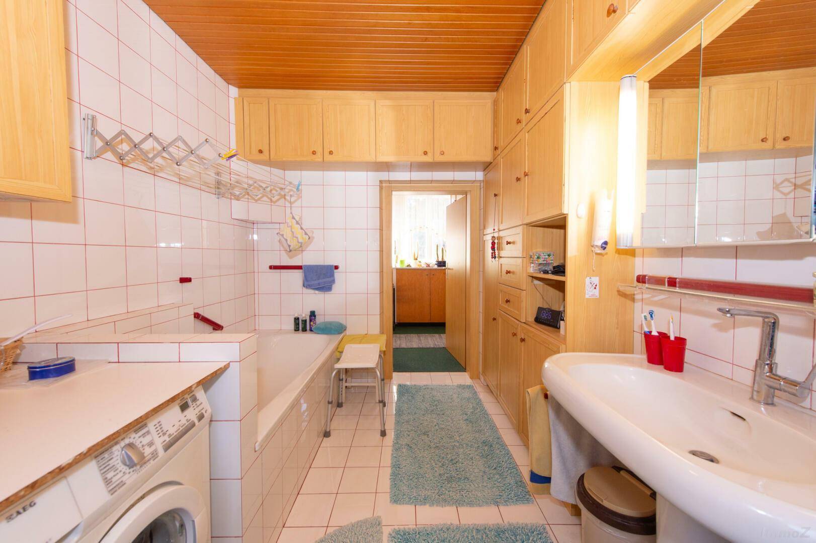 Geräumiges Badezimmer mit Badewanne, Waschbecken und viel Stauraum.