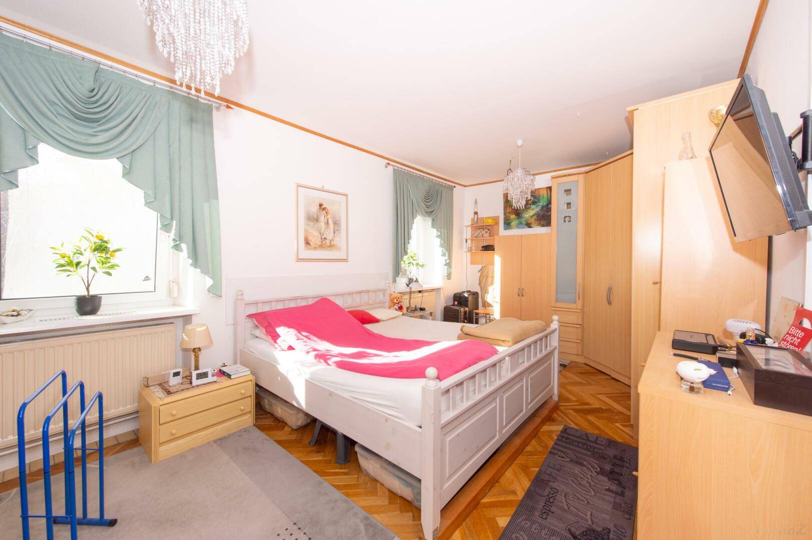 Schlafzimmer mit Parkettboden, Holzdecke und hellen Möbeln.