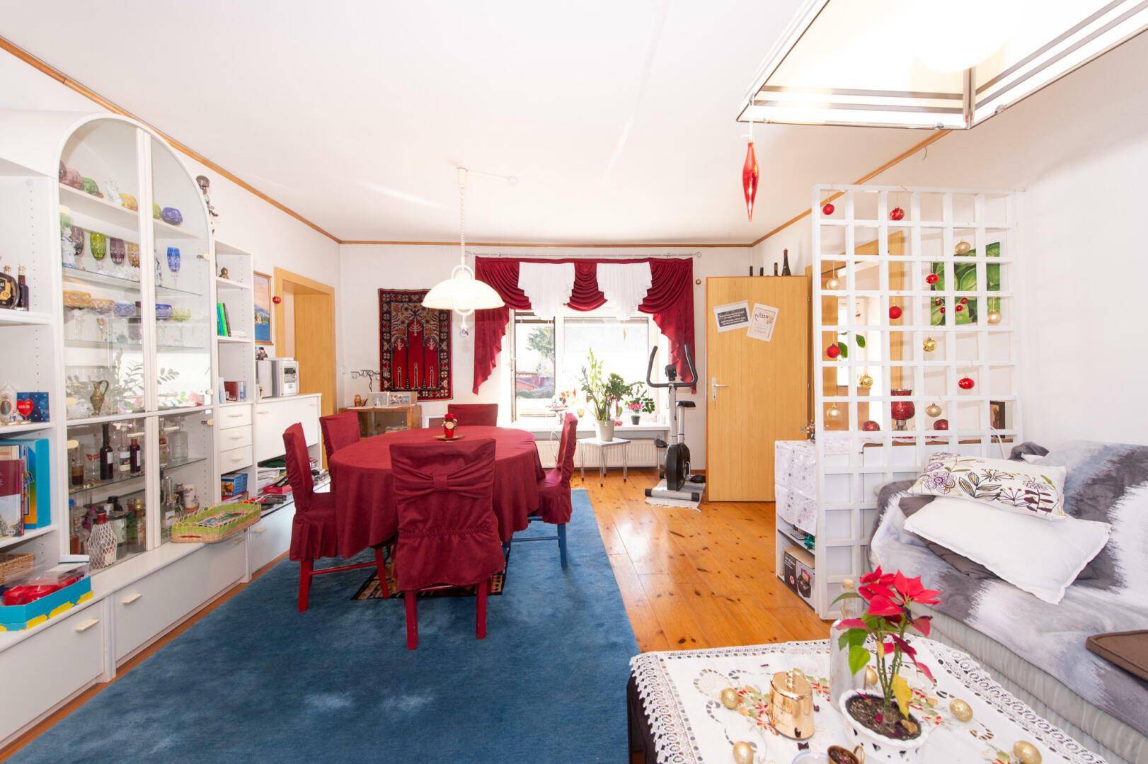 Heller Wohn-Essbereich mit Vitrinen, Esstisch und Holzboden.